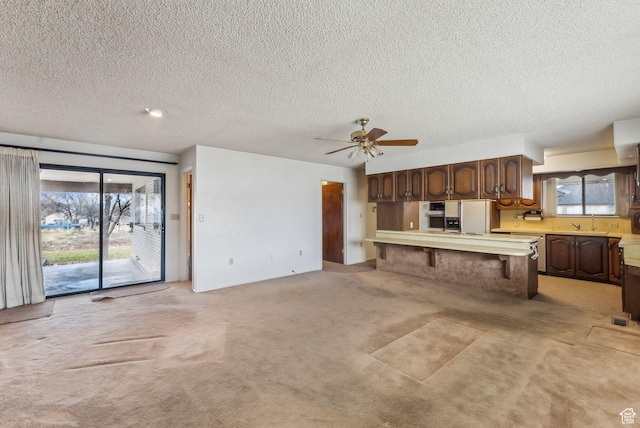 kitchen with ceiling fan, a kitchen bar, plenty of natural light, and kitchen peninsula