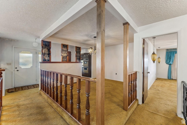 hall featuring a textured ceiling, an inviting chandelier, and carpet