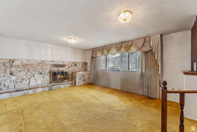 unfurnished living room with a textured ceiling, carpet, and a fireplace