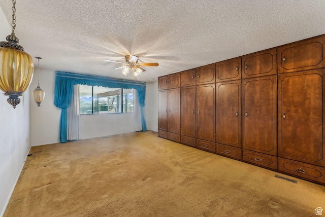 unfurnished bedroom featuring a textured ceiling, light carpet, and ceiling fan