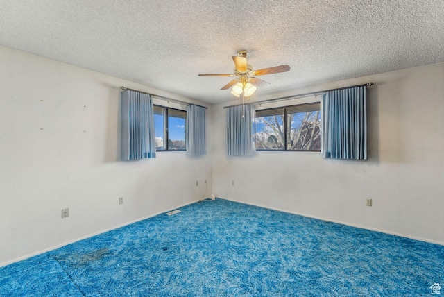 carpeted spare room featuring ceiling fan and a textured ceiling