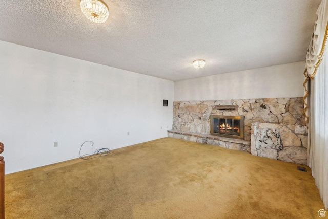 unfurnished living room featuring carpet flooring, a textured ceiling, and a stone fireplace