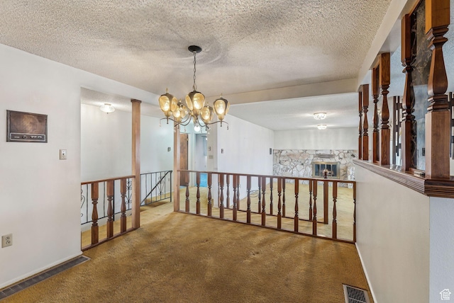 hallway featuring an inviting chandelier, a textured ceiling, and carpet flooring