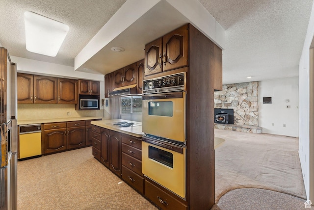 kitchen with a wood stove, double wall oven, dark brown cabinetry, white stovetop, and light colored carpet