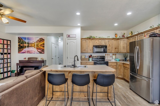 911 W 310 S, Pleasant Grove, UT 84062 - kitchen with black appliances, light wood-type flooring, a kitchen island with sink, a breakfast bar area, and sink