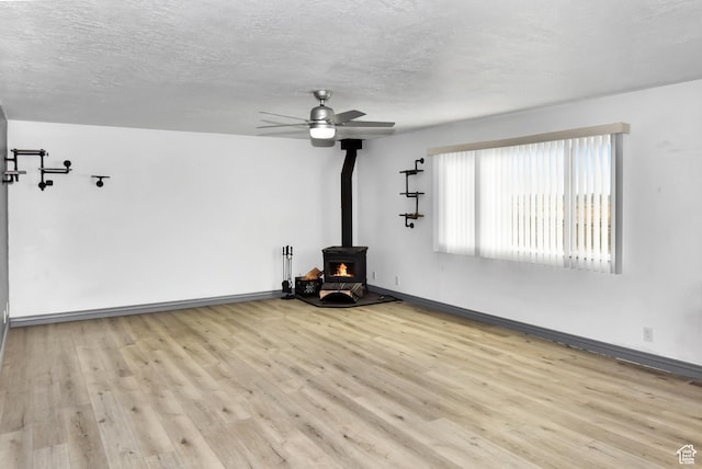 4752 E Max Rd, Downey, ID 83234 - unfurnished living room featuring ceiling fan, light wood-type flooring, a textured ceiling, and a wood stove