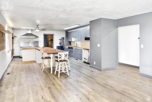 4752 E Max Rd, Downey, ID 83234 - kitchen with stainless steel appliances, butcher block countertops, sink, wall chimney range hood, and blue cabinets