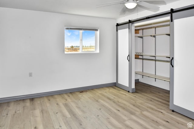 4752 E Max Rd, Downey, ID 83234 - unfurnished bedroom featuring ceiling fan, light wood-type flooring, and a barn door