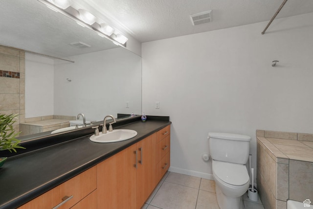 bathroom with a textured ceiling, tile patterned flooring, vanity, and toilet