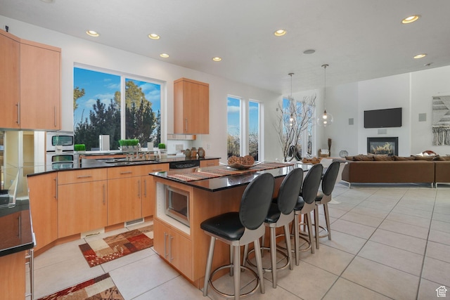 kitchen with a center island, light brown cabinetry, light tile patterned floors, and hanging light fixtures