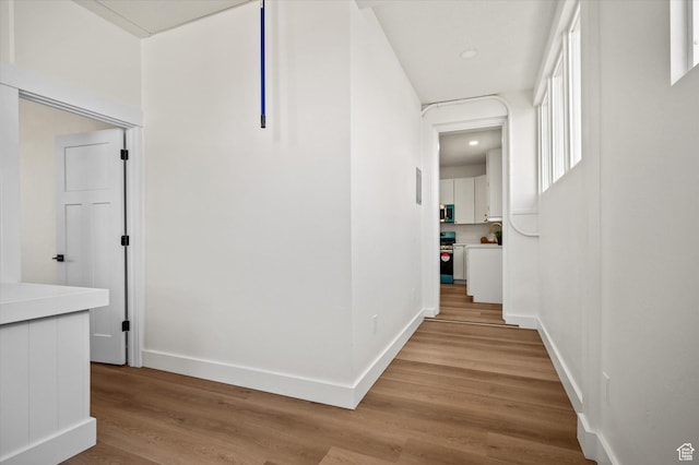 hall featuring light wood-type flooring, baseboards, and recessed lighting