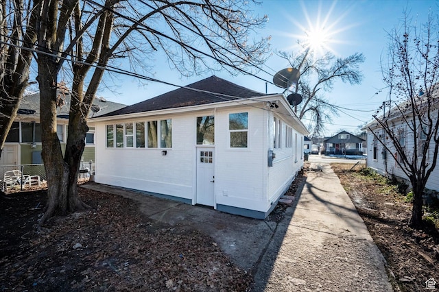 view of home's exterior with roof with shingles and brick siding