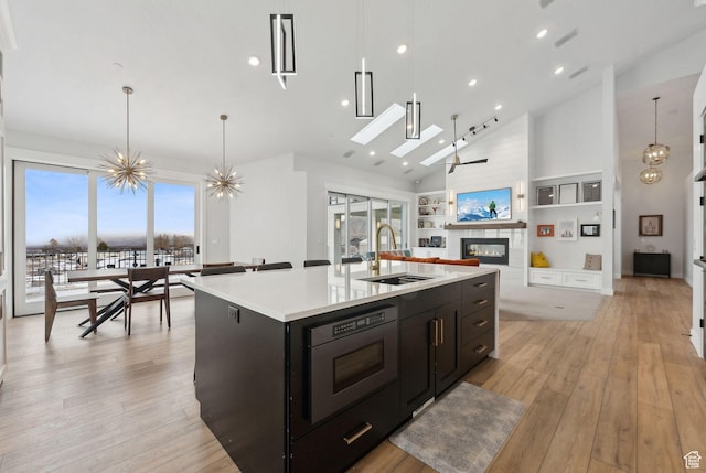 13599 S White Pony Rd W, Herriman, UT 84096 - kitchen with decorative light fixtures, sink, a large fireplace, a kitchen island with sink, and high vaulted ceiling