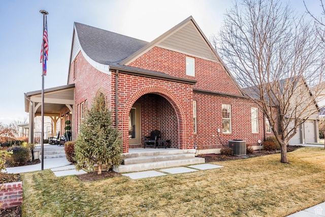 rear view of house with central AC unit, covered porch, brick siding, and a lawn