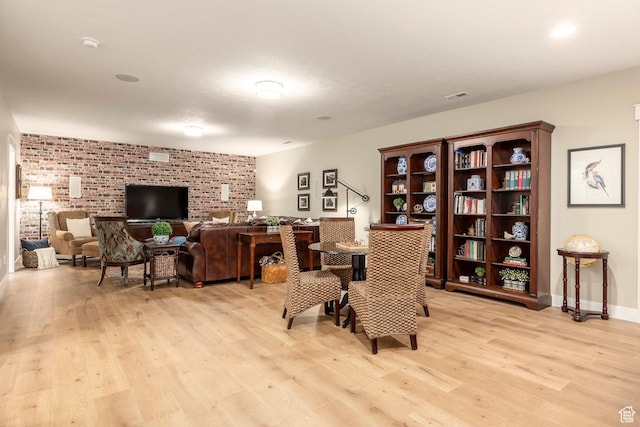interior space featuring visible vents, light wood-style flooring, brick wall, and baseboards