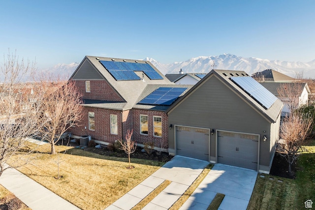 view of front of home with a front yard, driveway, an attached garage, central AC, and a mountain view