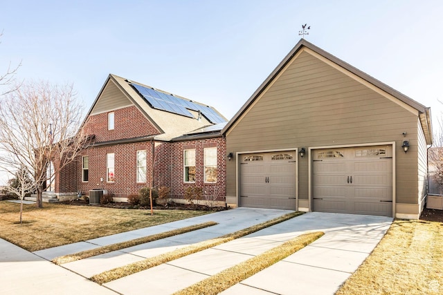 view of property exterior featuring brick siding, roof mounted solar panels, cooling unit, driveway, and an attached garage