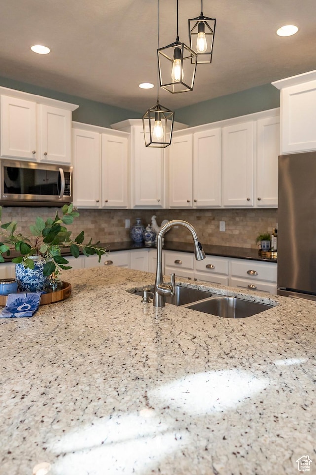 kitchen featuring a sink, decorative light fixtures, tasteful backsplash, appliances with stainless steel finishes, and white cabinets