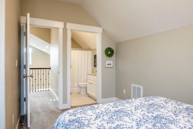 bedroom with baseboards, visible vents, lofted ceiling, light carpet, and connected bathroom