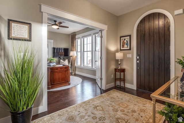 entryway with ceiling fan, baseboards, arched walkways, and dark wood finished floors