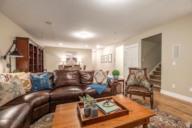 living area with stairway, light wood-style flooring, and baseboards