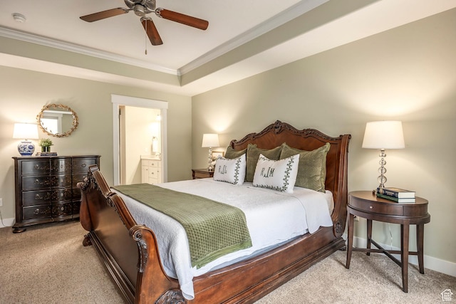 bedroom with baseboards, carpet floors, ensuite bath, a tray ceiling, and crown molding