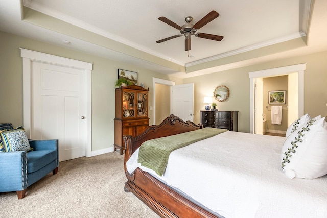 bedroom with a tray ceiling, light carpet, ensuite bath, and ornamental molding