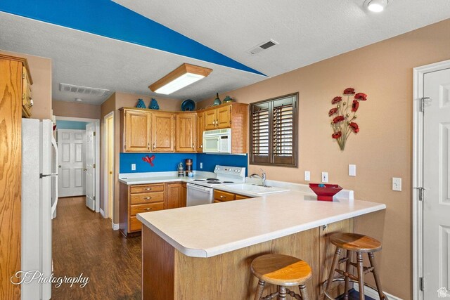 1050 W Red Hills Pkwy Unit 2, Washington, UT 84780 - kitchen featuring white appliances, kitchen peninsula, a breakfast bar area, and lofted ceiling