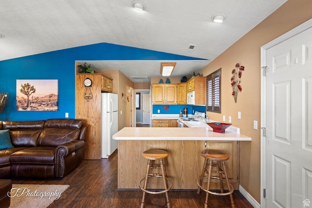 1050 W Red Hills Pkwy Unit 2, Washington, UT 84780 - kitchen with white appliances, vaulted ceiling, kitchen peninsula, a breakfast bar, and dark wood-type flooring