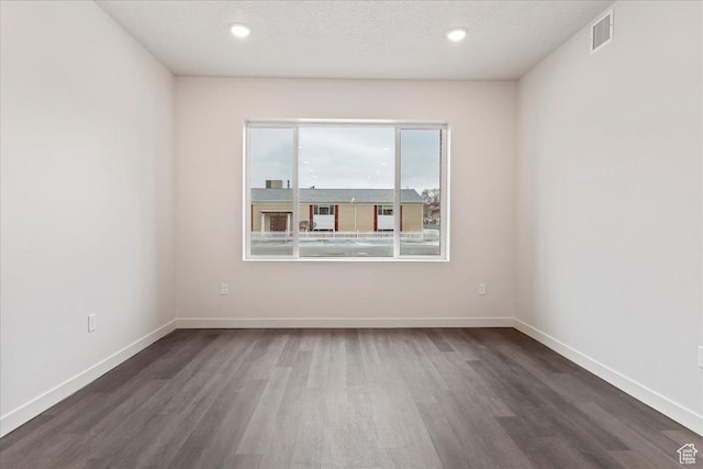 spare room featuring wood finished floors, baseboards, visible vents, recessed lighting, and a textured ceiling