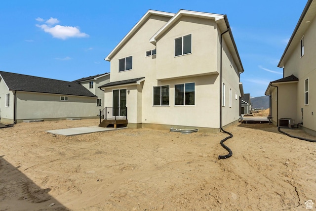 rear view of house with stucco siding and cooling unit