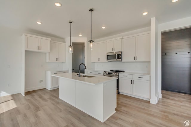 kitchen featuring an island with sink, light wood-style flooring, white cabinetry, appliances with stainless steel finishes, and a sink