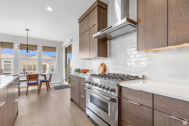 51 N Gray Fox Cir, Kaysville, UT 84037 - kitchen with high end range, pendant lighting, wall chimney exhaust hood, an inviting chandelier, and backsplash