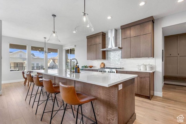 51 N Gray Fox Cir, Kaysville, UT 84037 - kitchen featuring range, light hardwood / wood-style floors, hanging light fixtures, a large island with sink, and wall chimney range hood