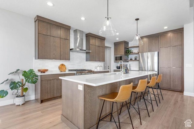 51 N Gray Fox Cir, Kaysville, UT 84037 - kitchen featuring wall chimney exhaust hood, a spacious island, light wood-type flooring, appliances with stainless steel finishes, and a kitchen breakfast bar