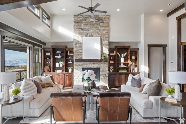 living room featuring ceiling fan, a fireplace, and a towering ceiling