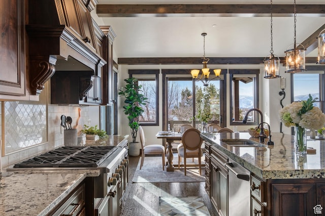kitchen featuring decorative light fixtures, sink, an inviting chandelier, stainless steel appliances, and light stone counters