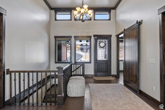 entrance foyer with a barn door, dark wood-type flooring, a wealth of natural light, and a chandelier