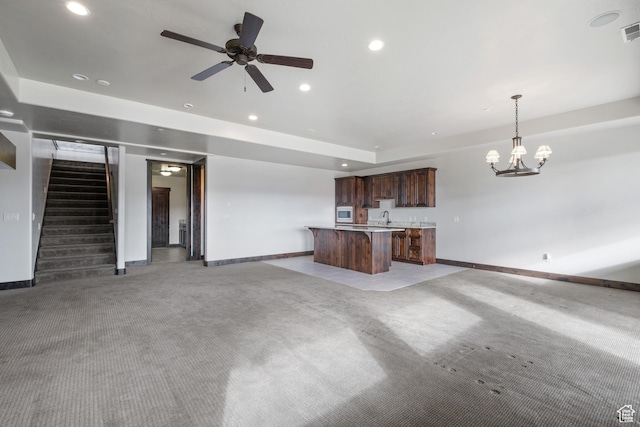 unfurnished living room featuring light colored carpet and ceiling fan with notable chandelier
