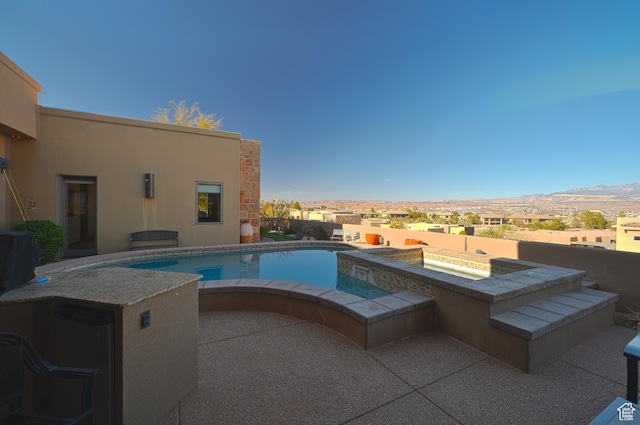 view of pool featuring an in ground hot tub, a patio area, and a mountain view