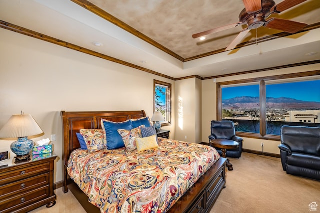 carpeted bedroom featuring ceiling fan, crown molding, and a raised ceiling