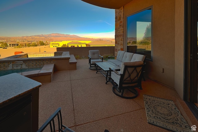 patio terrace at dusk with a mountain view, an outdoor kitchen, and an outdoor living space