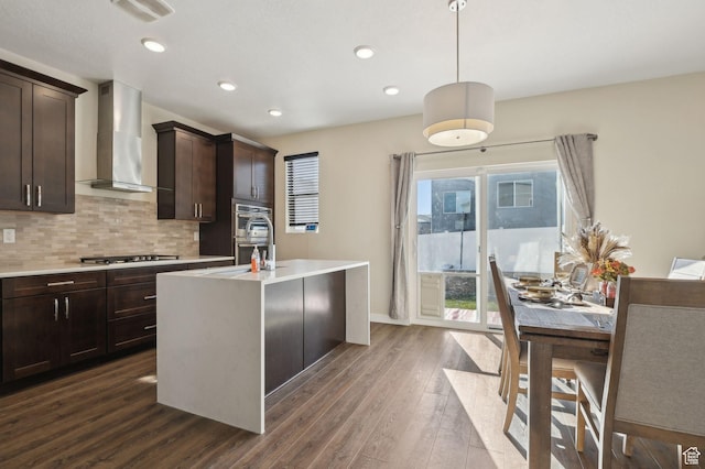 6343 W 7900 S, West Jordan, UT 84081 - kitchen featuring wall chimney range hood, pendant lighting, a center island with sink, stainless steel gas cooktop, and dark hardwood / wood-style flooring