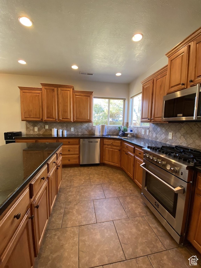 1918 S Mojave Dr, Washington, UT 84780 - kitchen featuring tile patterned flooring, stainless steel appliances, dark stone counters, decorative backsplash, and sink