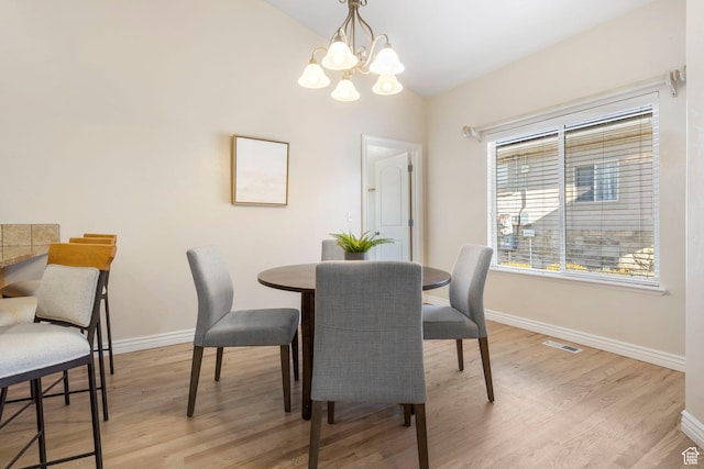 dining space featuring lofted ceiling, an inviting chandelier, and light hardwood / wood-style flooring