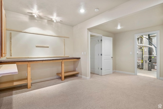 basement featuring light carpet, rail lighting, and gas water heater