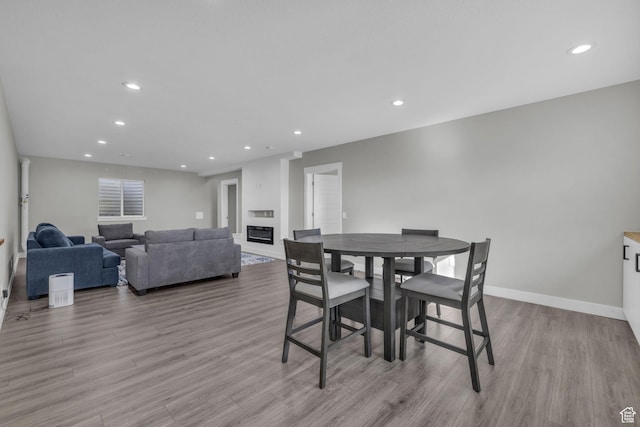 dining space with light wood-type flooring and a large fireplace