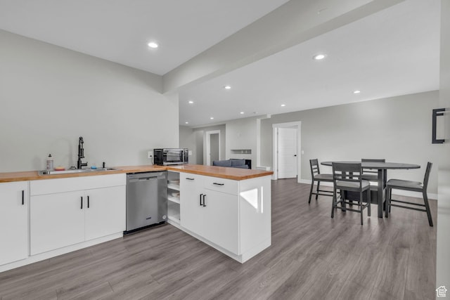 kitchen with white cabinets, dishwasher, sink, and butcher block countertops
