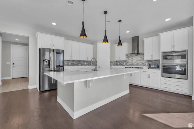 kitchen with wall chimney range hood, white cabinets, and stainless steel appliances