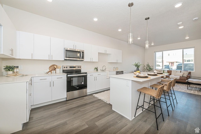kitchen with dark hardwood / wood-style floors, appliances with stainless steel finishes, white cabinetry, and hanging light fixtures